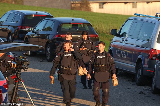 Law enforcement officers pass media gathered during the manhunt on October 28, 2024 near Rohrbach, Austria