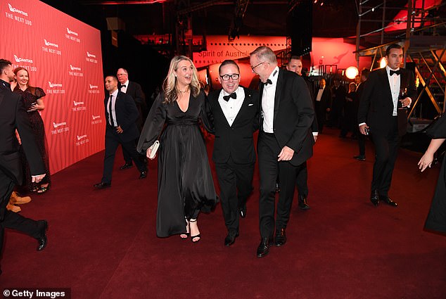 Former Qantas CEO Alan Joyce proudly walks the red carpet with one arm around the Prime Minister and the other around his partner Jodie Haydon