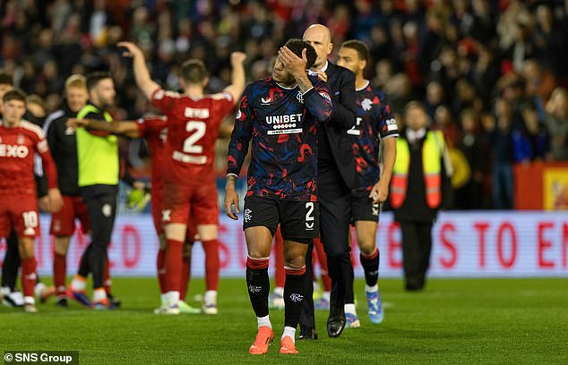 Rangers skipper James Tavernier leaves the field as the victorious Dons stars celebrate