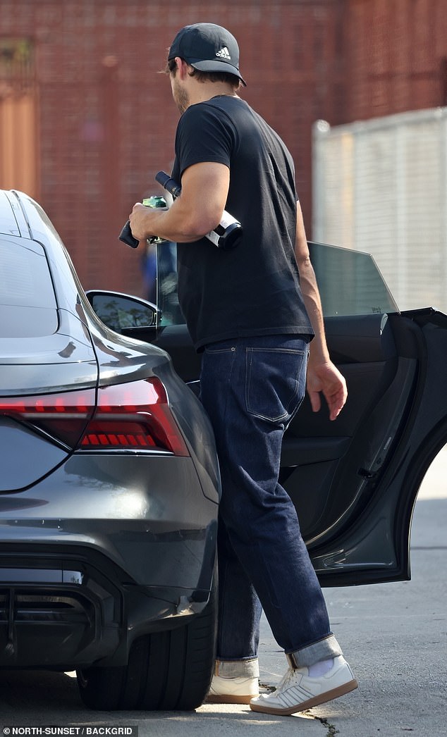 For the outing, Tom cut a casual figure in a black T-shirt and dark trousers, which he paired with white trainers while loaded down with the gear.