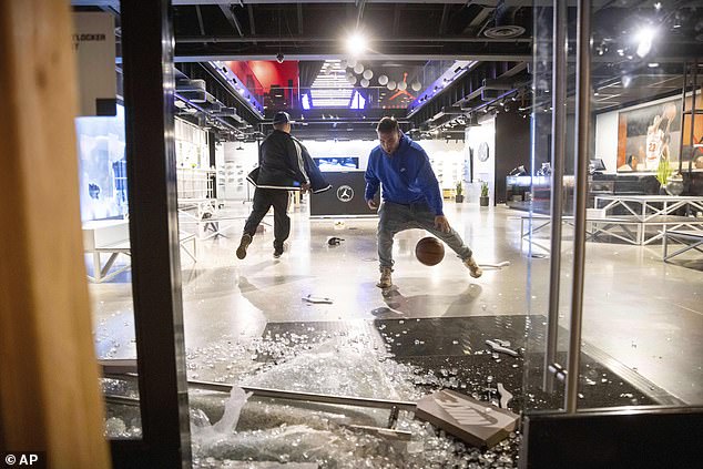 Looters are seen playing basketball in a vandalized Nike store in downtown LA