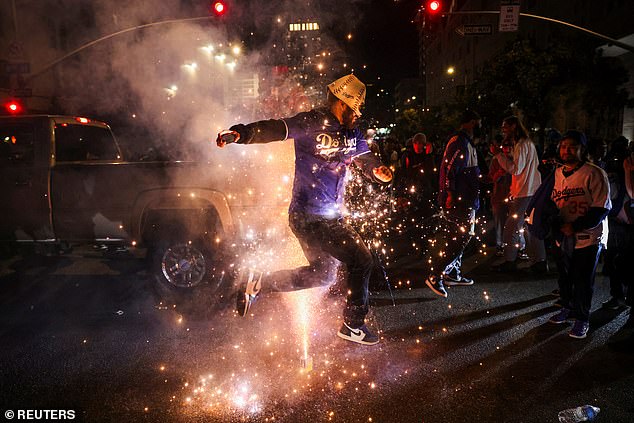 One fan in a Dodgers jersey jumps over a fireworks display during the wild festivities in Los Angeles