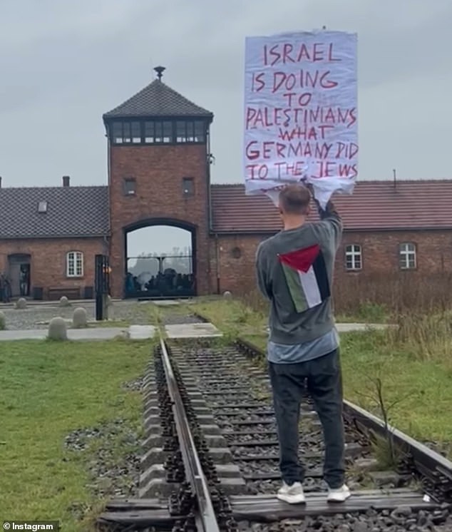 A Polish artist has sparked outrage after standing outside the former Nazi death camp Auschwitz with a sign that read: 'Israel is doing to the Palestinians what the Germans did to the Jews'