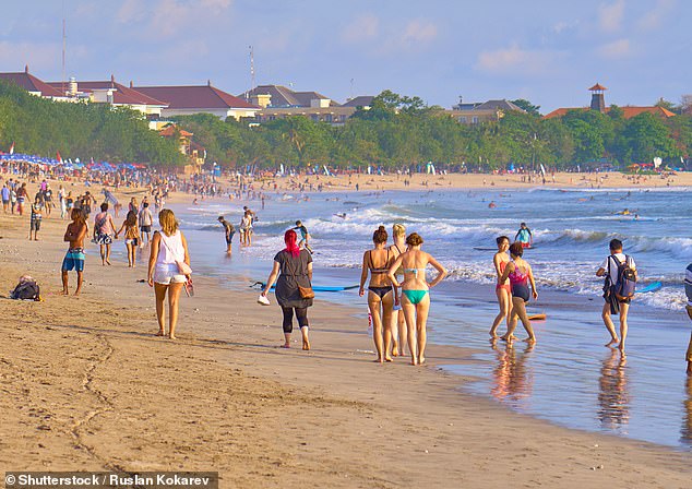 Tourists could spend up to 20 years in a prison cell in Bali if they are found to have overstayed their visa or broken immigration laws, under new tough measures (pictured on Kuta Beach)