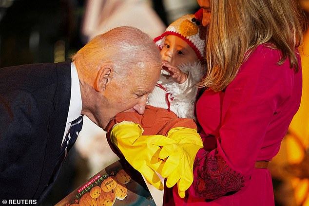 Joe Biden playfully bites a baby while trick-or-treating at the White House