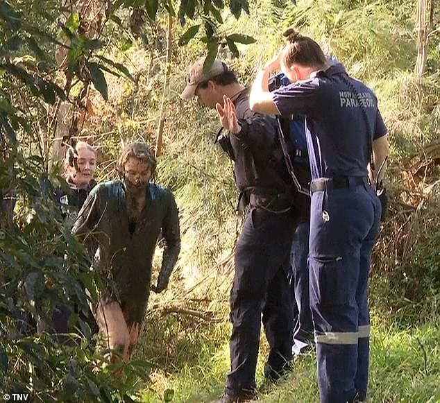 Elle Booth is escorted out of the muddy creek by officers on July 9, 2023