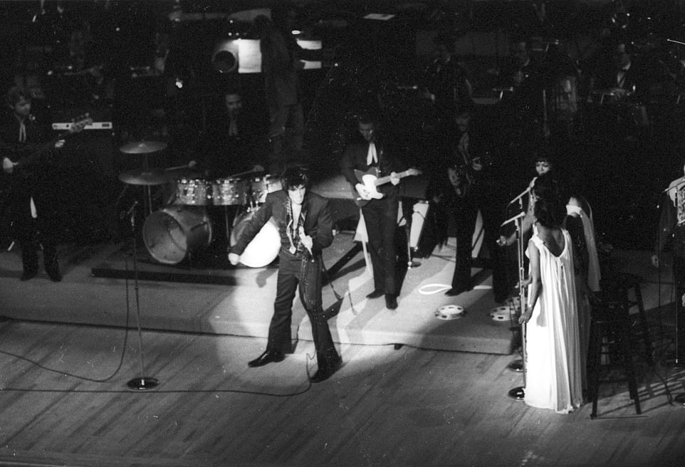 Elvis Presley performing on stage with his backup singers The Sweet Inspirations in 1973 in Las Vegas