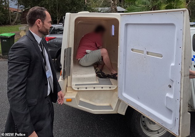 The man sits in the back of a police van on Wednesday after he was arrested