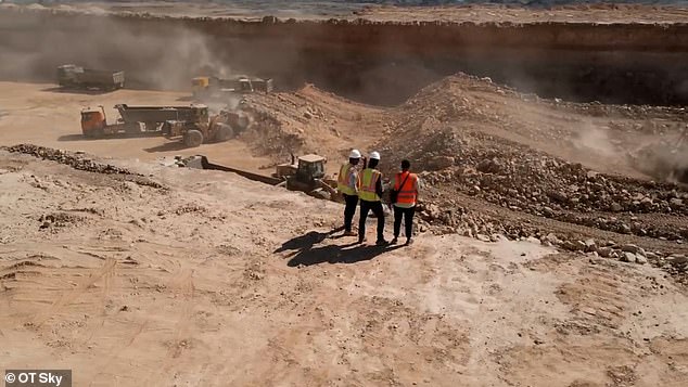 Construction workers stand at the edge of a huge ditch being dug for the megacity The Line