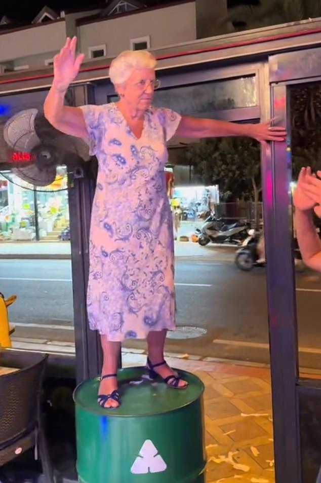 In the clip, the white-haired grandmother (pictured) sits low and waves her hands in the air as she is cheered on by other partygoers