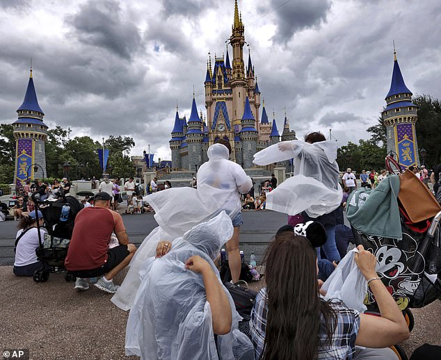 Magic Kingdom guests take off ponchos at Cinderella Castle as the weather from Hurricane Helene moves through Walt Disney World on Thursday, September 26, 2024