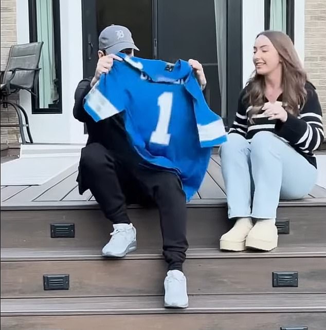 While sitting outside on a patio, his daughter handed him a blue shirt which he held up to show that 