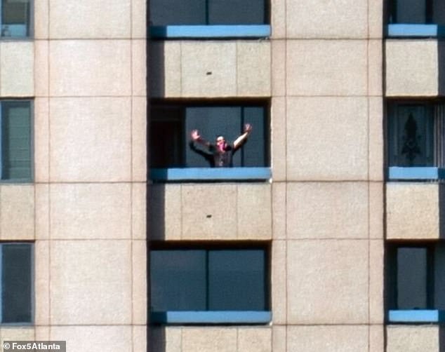 A terrifying photo of a masked man on the balcony of the Four Seasons hotel in Atlanta, where he opened fire on a nearby building