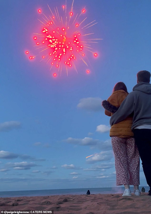 The family fireworks are set off over the ocean view, lighting the sky with red and orange hues