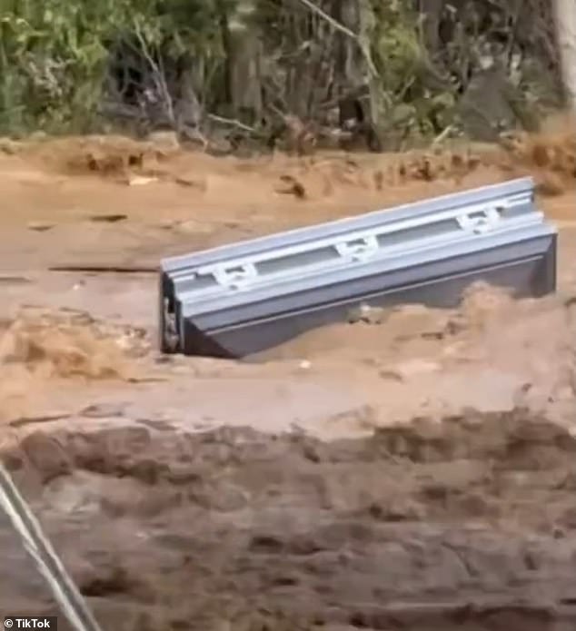 The gruesome clip shows a coffin being thrown through muddy floodwaters in Erwin, Tennessee