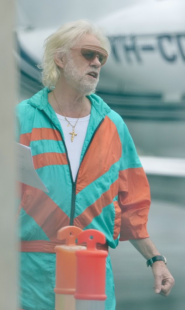 An iconic singer looked almost unrecognizable as he stepped out for filming at a Gold Coast airport on Monday morning