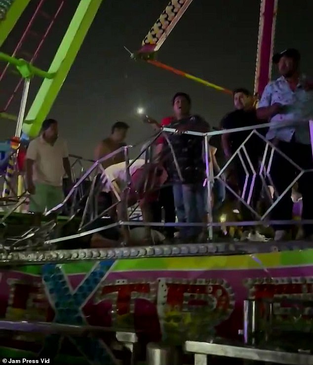 People are seen standing next to battered barriers at the base of the ride