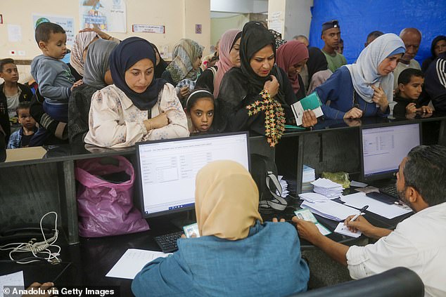 Palestinians wait in a line at an UNRWA clinic in Deir-al-Balah to receive medicine and medical treatment