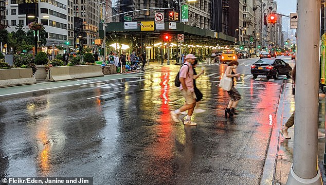 Pedestrians walked down a New York street on a rainy day (photo). The Jaywalking laws disproportionately targeted people of color