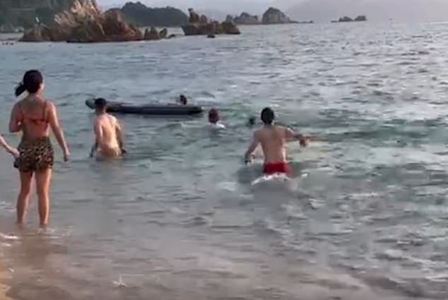 Bystanders can be heard screaming in panic, with one person throwing a paddleboard at the man to get him to safety