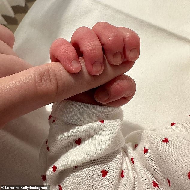 The TV presenter beamed as the adorable toddler's face was seen for the first time after fans were only teased by a glimpse of her tiny feet and hands