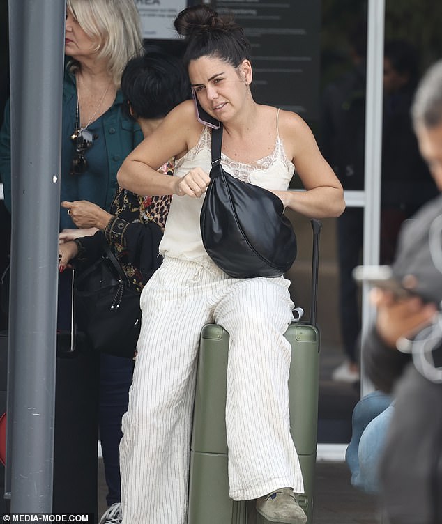 Home And Away's Emily Weir was spotted returning to Sydney from the US last week. The actress was dressed in a white outfit as she sat on her green luggage and took a call. Emily looked animated while on the phone as she went for a casual, boho look with her outfit. She wore a lace-trimmed top and white pinstripe pants. Pictured