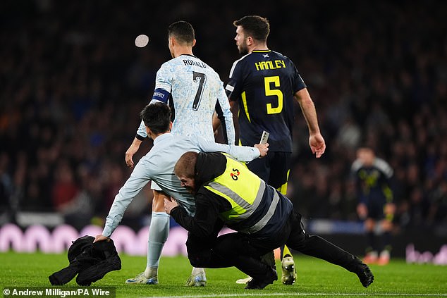 A pitch intruder is being tackled after breaching Hampden security in an attempt to reach Ronaldo