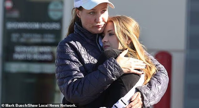 Two women embrace outside the dealership after a shocking incident