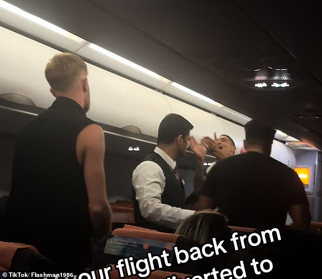 Staff separate two men as they clash on the flight returning to London Gatwick on Tuesday