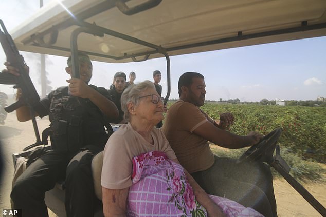 Palestinians transport a captured Israeli citizen, center, from Kibbutz Kfar Azza to the Gaza Strip on Saturday, October 7, 2023