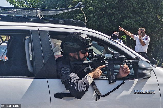 An Israeli police officer points his weapon from a vehicle after a suspected stabbing attack in Hadera, Israel, October 9, 2024