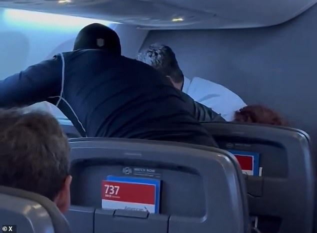 Video shared online shows several men leaning over a man who was sitting in the front row of the flight from Miami, Florida to Charlotte, North Carolina on Wednesday