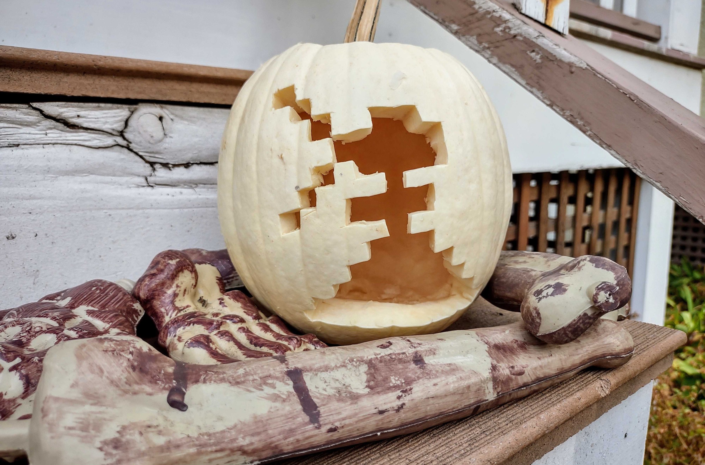 An 8-bit, pixelated figure is cut into the surface of a white pumpkin. 