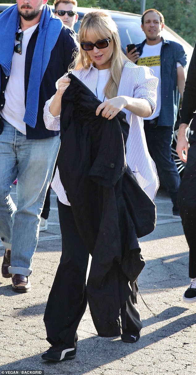 For the high-profile sporting event, the actress wore loose-fitting black pants, a white T-shirt and a white button-up shirt with blue stripes.