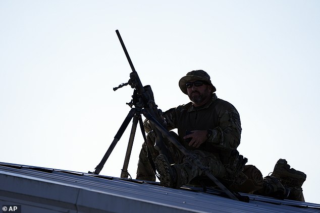 A counter-sniper positions himself on the roof of a building before Republican presidential candidate, former President Donald Trump, speaks during a campaign rally at the Butler Farm Show, the site where a gunman tried to kill him on Saturday, October 5, 2024. in Butler, Pa