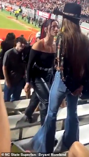 A woman in all black approached another fan wearing a cowboy hat