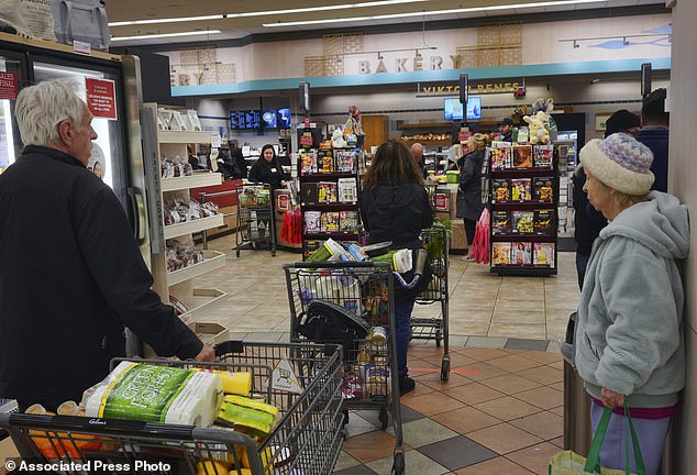 Shoppers wait in line to purchase groceries at a Gelson's supermarket on Friday, March 20, 2020 in the Sherman Oaks neighborhood of Los Angeles