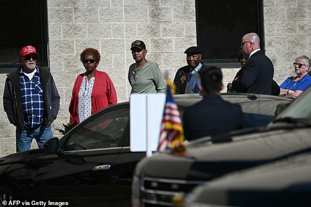 The 81-year-old president walked past a voter (left) wearing a MAGA hat with the message