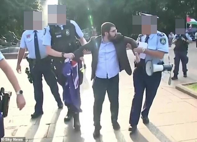 The arrest of Osher Feldman (pictured center), who carried an Australian flag during a pro-Palestinian protest on Sunday, has outraged the Jewish community.