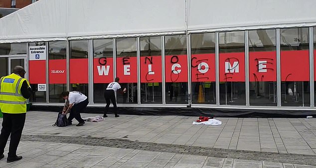 Two supporters of the Youth Demand organization are pictured holding a spray can with the words 'Genocide Conference' on the main entrance to the Labor Party conference