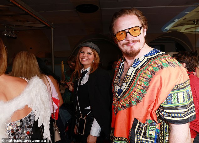 Wearing a black leather mini skirt, black tie and old-fashioned hat, she worked on her angles as she joined NRL player George Burgess, who went for a completely different look. The former St George Illawarra player, 32, went for a 1960s hippie look, complete with paisley shirt and yellow lens glasses. Both shown