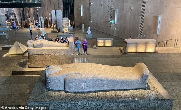 Visitors to the Grand Egyptian Museum explore massive stone sarcophagi