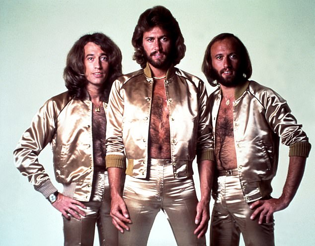 Disco group the Bee Gees poses for a portrait in gold-colored outfits in 1977