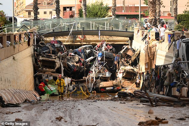 Members of the fire brigade, part of a search and rescue unit, carry out work as cars and rubble block a tunnel following the recent flash floods in the nearby municipality of Benetusser on November 1