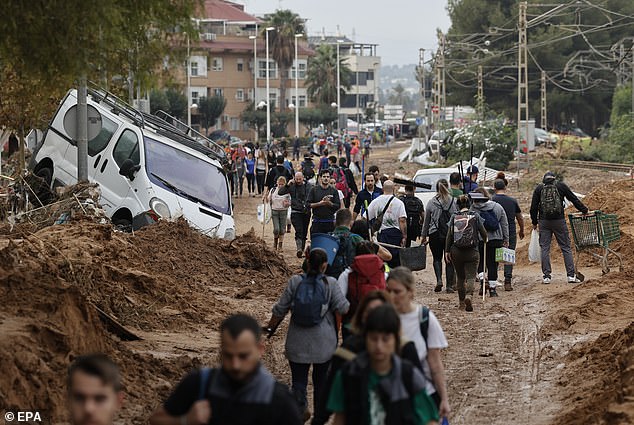 People walk through an affected area of ​​Paiporta, Vallencia. The streets are filled with flood sediment and broken cars due to the force of the water