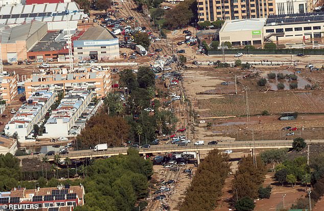 Aerial photo shows muddy roads near Valencia covered in wrecked cars and other debris