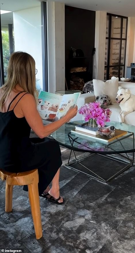 The TV icon, wearing a black slip dress and sandals, was seen sitting on a wooden stool as she read Clydeo Takes a Bite Out Of Life – published on October 1 – to her doggy audience as they lounged on her sofa .