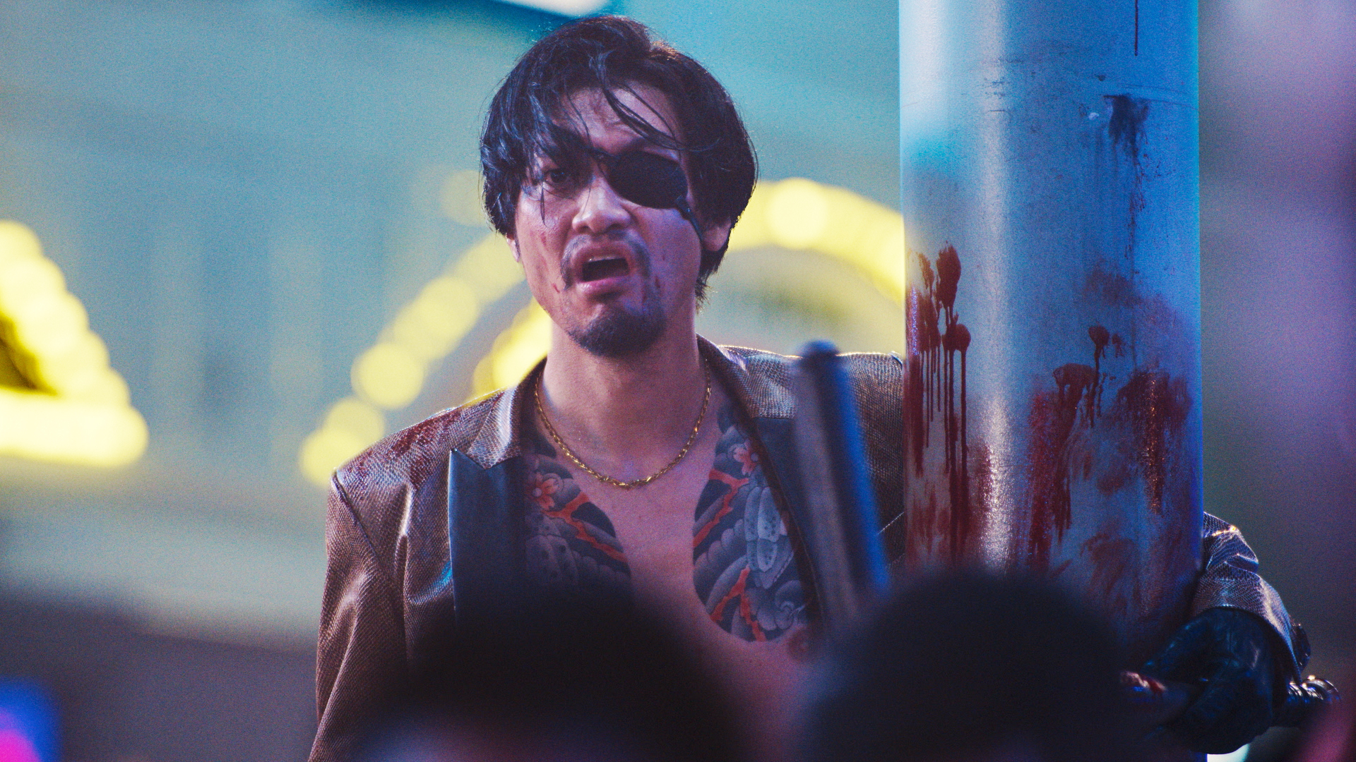 Majima (Munetaka Aoki) looks shocked with an eye patch as she hugs a bloody poll in Like a Dragon: Yakuza