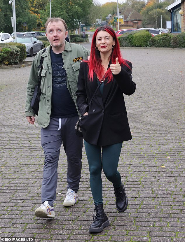 Dianne smiled as she walked around in a green unitard with a black button-up jacket and black Dr. Marten boots, while Chris kept it casual in a green jacket, blue T-shirt and gray sweatpants.