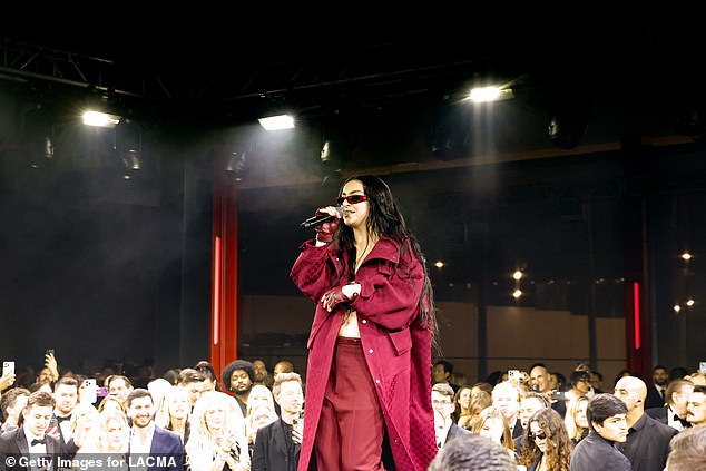 The Boy Singer let loose her long, dark locks and draped a matching red jacket off her shoulders as she danced across the stage in the center of the room.